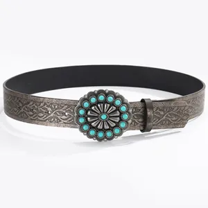 Detail of western cowboy belt buckle with turquoise inlay and embossed leather
