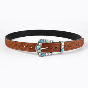 Detail of silver western belt buckle with turquoise stones and embossed floral leather