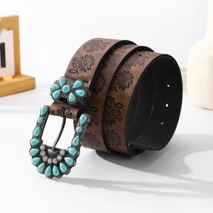 Detail of bohemian brown leather belt featuring turquoise buckle and floral embossing