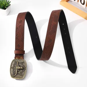 Detail of vintage brown leather belt with embossed floral patterns and bull head metal buckle