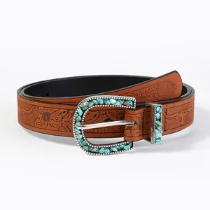 Close-up of brown leather belt with floral embossing and turquoise horseshoe buckle