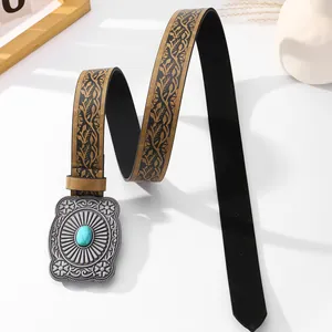Close-up of vintage metal buckle with embossed flower and inlaid turquoise on leather belt