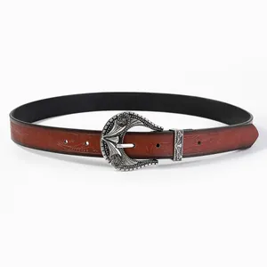 Detail of vintage reddish-brown embossed leather belt with ornate silver metal buckle