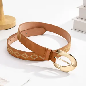Dettaglio cintura in pelle marrone con ricami geometrici dorati e fibbia in metallo lucido