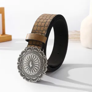 Detail of vintage silver round buckle and embossed crocodile pattern on brown leather belt