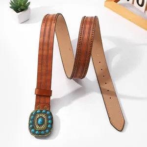 Detail of vintage brown leather belt featuring embossed patterns and blue turquoise buckle