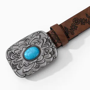 Close-up of vintage silver buckle with turquoise stone on embossed brown leather belt