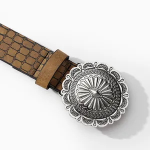 Detailed close-up of vintage brown belt with crocodile pattern and silver engraved buckle