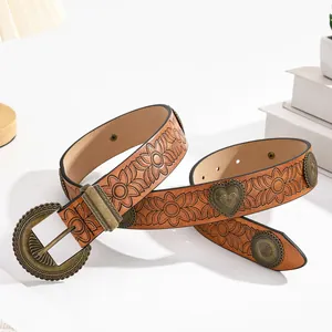 Détail d'une ceinture en cuir marron vintage avec gaufrage floral et rivets en cœur