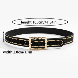 Macro shot of black belt with gold wave embroidery and a textured square metal buckle