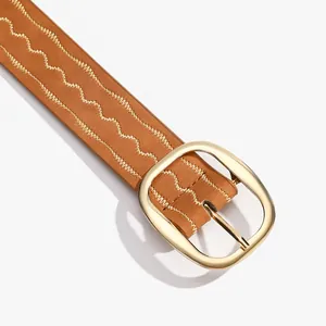 Détail d'une ceinture en cuir marron avec boucle dorée ovale et surpiqûres décoratives