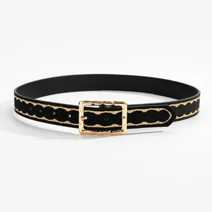 Close-up of black leather belt featuring gold wavy stitching and a hammered metal buckle