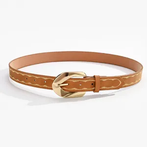Détail d'une ceinture marron avec boucle fer à cheval dorée et broderie ondulée élégante