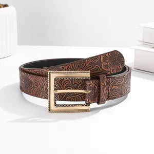 Detailed macro view of vintage brown leather belt with embossed floral pattern and gold buckle