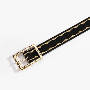 Detailed macro view of black leather belt featuring gold wavy stitching and hammered metal buckle