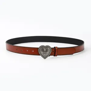 Détail de la boucle cœur vintage avec relief en croix sur ceinture en cuir marron