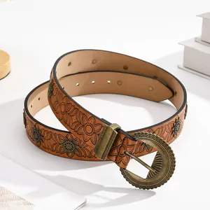 Vintage brown leather belt with floral embossing and sunburst metal rivets on white block
