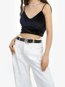 Close-up of vintage leather belt with silver buckle and amber gemstones on white pants
