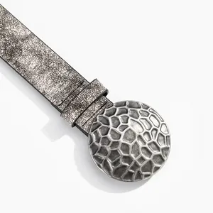 Dettaglio macro della fibbia tonda retrò e trama vintage sulla cintura da donna di stile