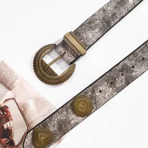 Détail de ceinture en cuir gris argenté vintage avec boucle bronze et clous métalliques