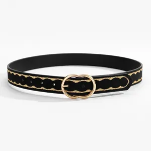 Close-up of black suede belt with gold wavy embroidery and a metal double ring buckle