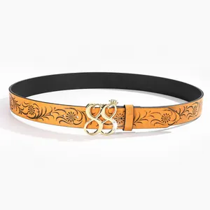 Detail of Y2K yellow leather belt with vintage floral pattern and gold crown buckle