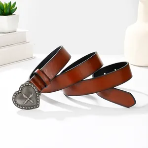 Détail de la boucle cœur argentée vintage avec gravure croix sur ceinture en cuir marron