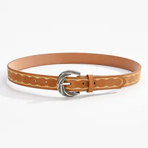 Détail d'une ceinture en cuir beige style western avec broderie et boucle argentée ciselée