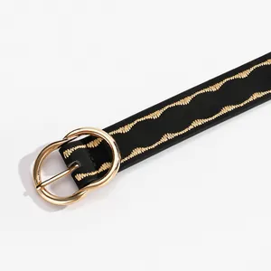 Detail of the golden double ring buckle and wavy embroidery on the black leather belt