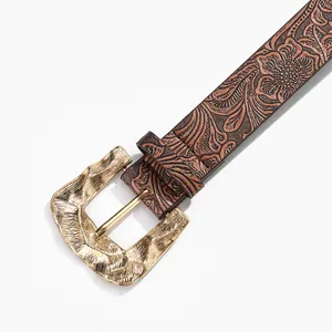 Detailed close-up of dark brown leather belt with vintage floral embossing and gold buckle