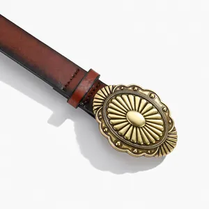 Gros plan d'une boucle ovale en bronze vintage sur une ceinture en cuir marron texturé