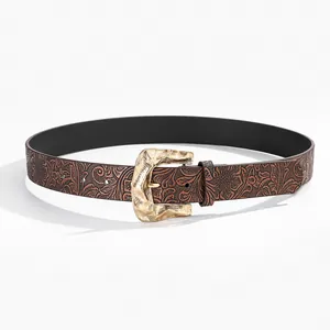 Detailed macro view of embossed floral leather belt with hammered gold buckle