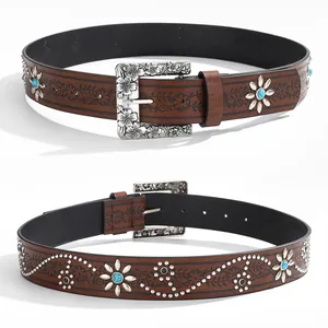 Close-up view of a vintage brown leather belt featuring floral buckle and turquoise studs