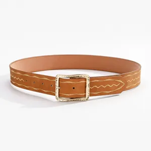 Détail d'une ceinture en cuir marron avec broderie ondulée et boucle dorée martelée