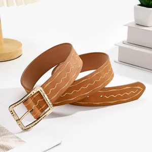 Détail d'une ceinture marron avec broderie vagues dorées et boucle en métal martelé