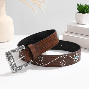 Detail of bohemian brown leather belt featuring floral embossing and turquoise studs
