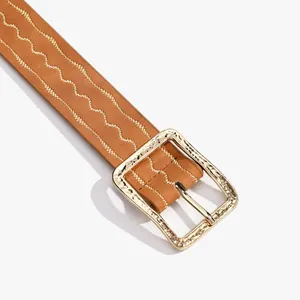 Détail d'une ceinture en cuir marron avec broderie dorée et boucle en métal martelé