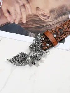 Dettaglio della fibbia in metallo con aquila e cintura in pelle con motivi floreali