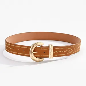 Détail de ceinture en cuir marron avec surpiqûres dorées et boucle fer à cheval mate