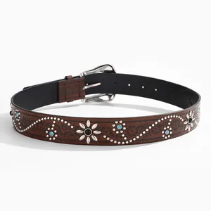 Close-up of bohemian leather belt with floral embossing, silver studs and turquoise stones