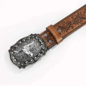 Detail of western vintage leather belt featuring embossed floral patterns and longhorn buckle