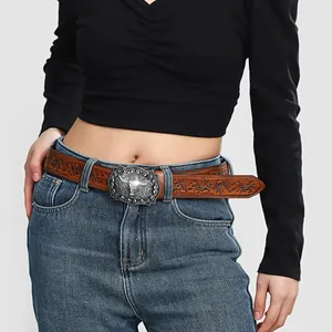 Western style brown embossed leather belt with silver bull head buckle on blue jeans