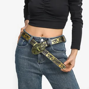Dettaglio cintura western con fibbia a testa di toro bronzata su jeans denim blu