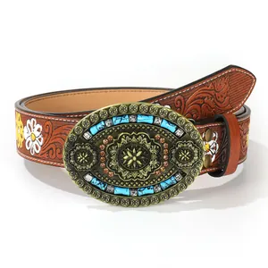 Macro detail of western belt featuring floral embossing and turquoise buckle with sunflower