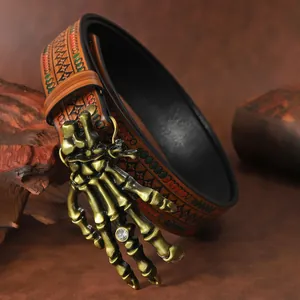 Detailed shot of bronze skull hand buckle with diamond accent on embossed leather belt