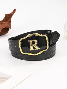Detail van heren lederen riem met reliëf bloemmotief en gouden R-vormige gesp