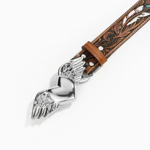 Close-up of western vintage belt buckle featuring a silver winged heart and floral embossing