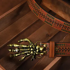 Close-up of bronze skull hand belt buckle with crystal on embossed brown leather strap