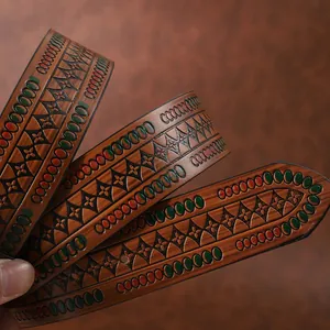 Detailed close-up of brown leather belt with embossed floral patterns and colorful studs