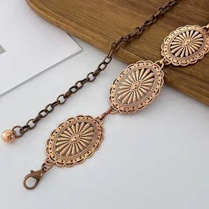 Detailed macro view of vintage bronze embossed metal waist chain with sunburst patterns